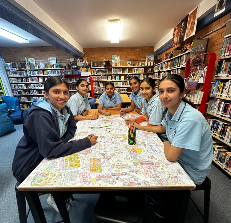 A group of Indian students sitting around a colourful table in the library