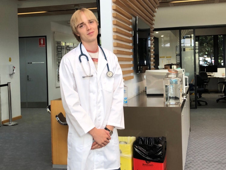 A young trainee doctor wearing a white coat with a stethoscope around his neck