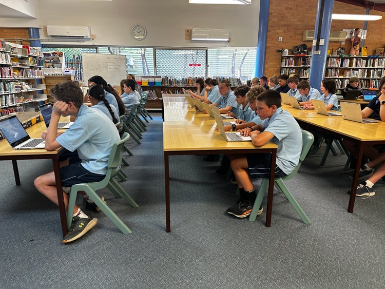 Students sitting a desks working on laptop computers