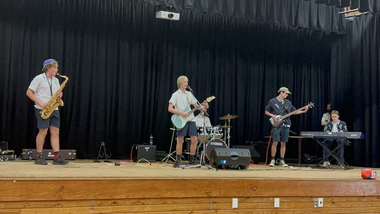 Senior students playing instruments and singing in a band performing on a timber stage