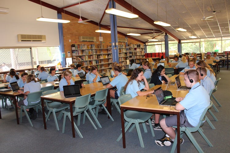 Students sitting at desks with headphones on working on laptops