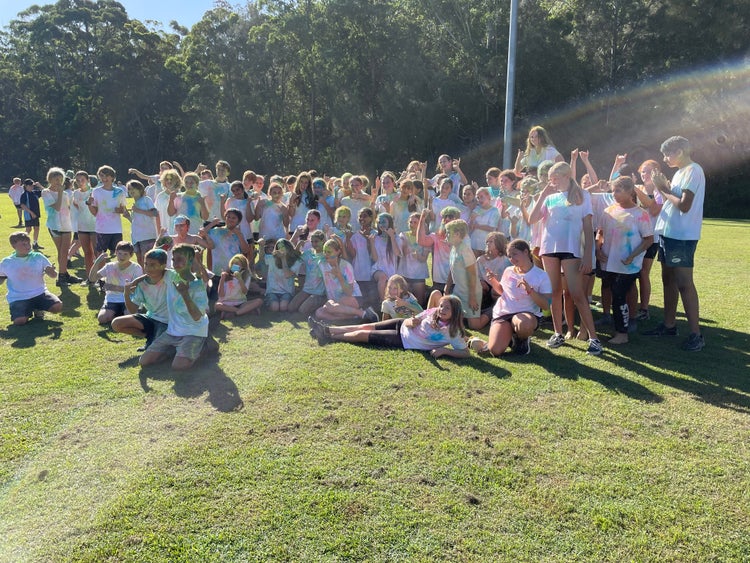 A group of students wearing white t-shirts covered in colourful chalk after having a colour run.